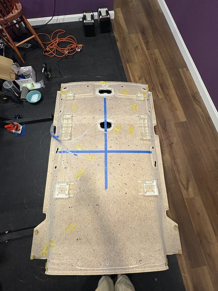 Headliner panel removed and laid out on the floor with hundreds of fiber-optic strands fanning from a taped bundle