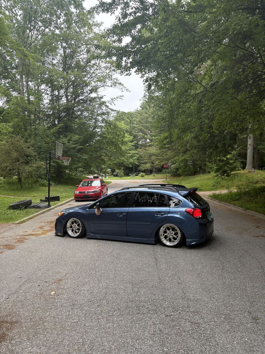 Lowered blue Subaru Impreza hatchback parked in a driveway
