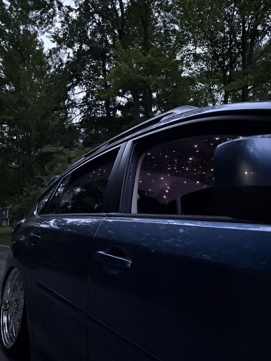 Warm white stars glowing in the rear ceiling of a hatchback at dusk