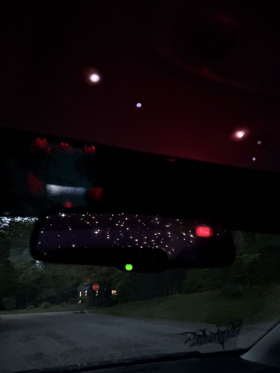 Interior at night with warm white stars in the ceiling reflected in the rearview mirror